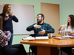 Several adults learning hand gestures in a class setting.