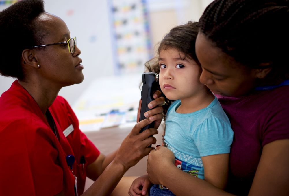 A doctor looking at a child's ear with a light.