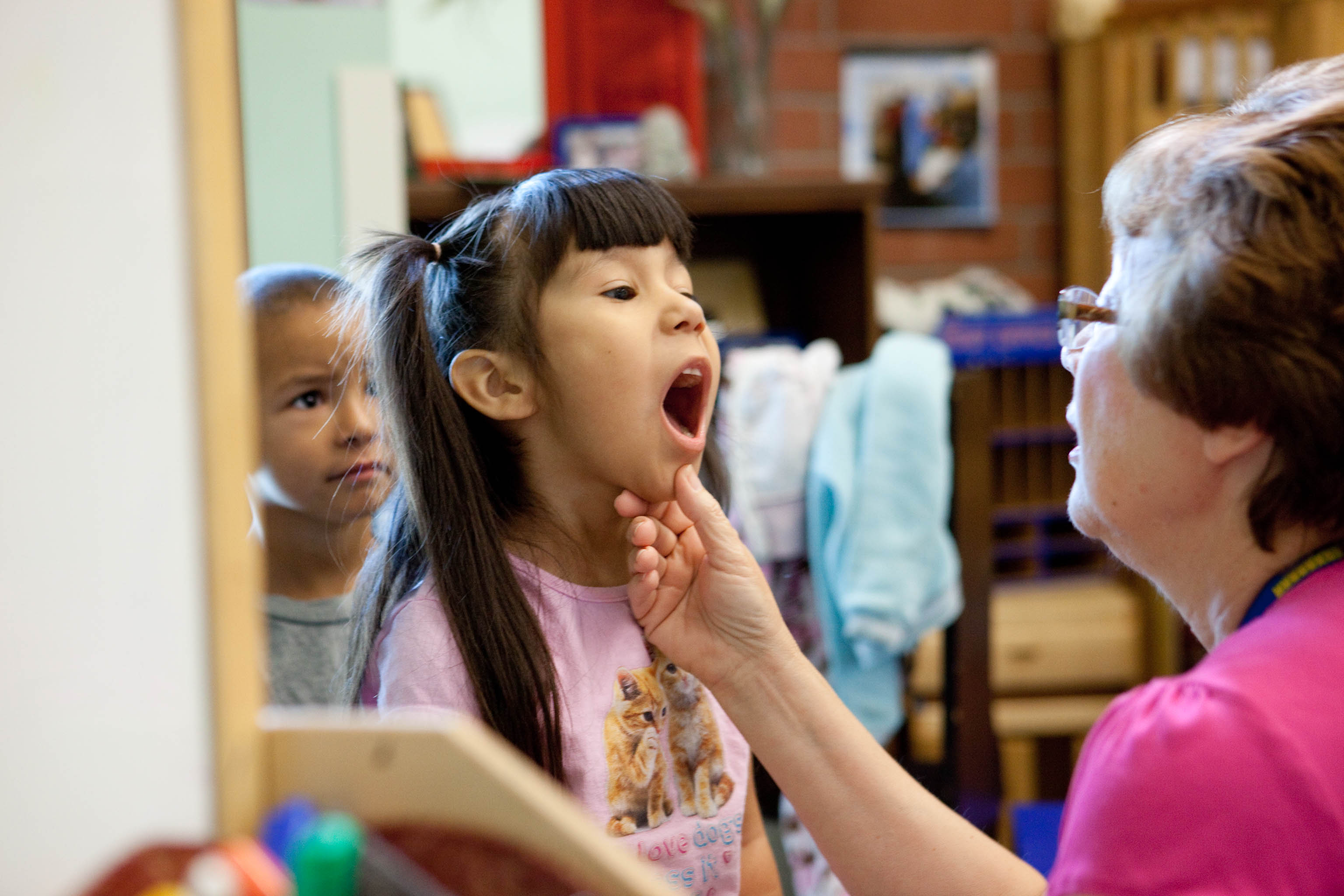 Girl opening her mouth wide so that doctor can check her tonsils.