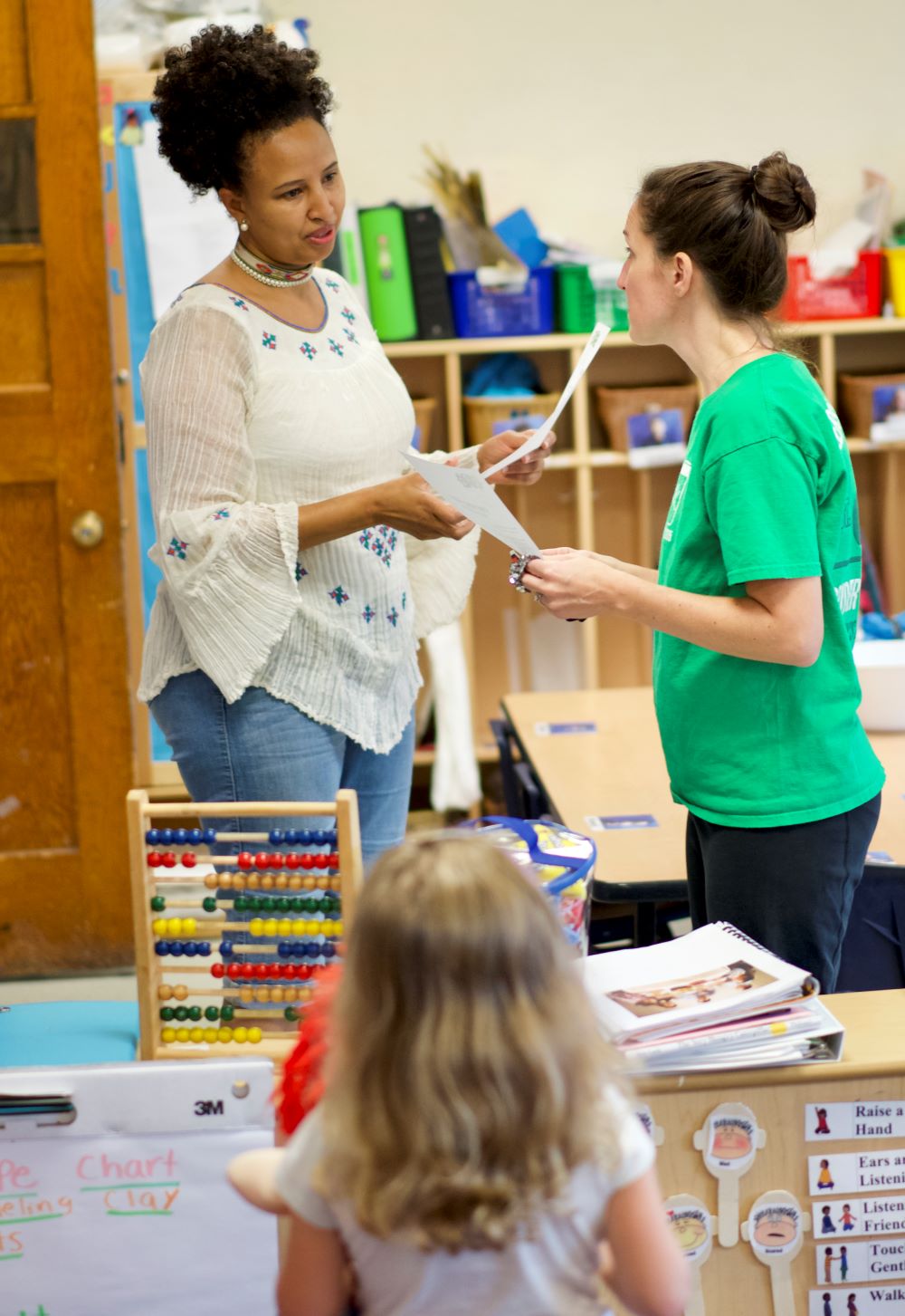 Two women talking while a young girl looks on.