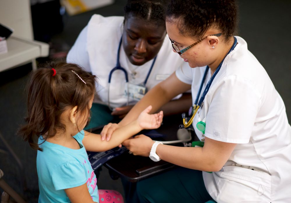 Health staff taking a child's pulse.