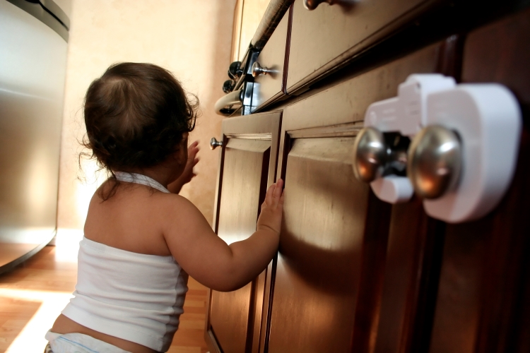 Niño caminando más allá de los gabinetes de cocina con cerraduras de seguridad para niños.