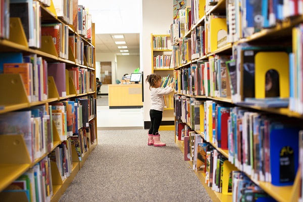 Niño buscando un libro en una biblioteca