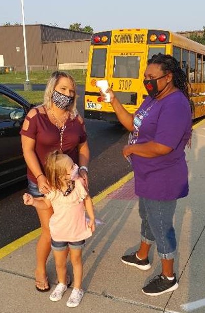 Bus assistant talking with mother at the bus stop.