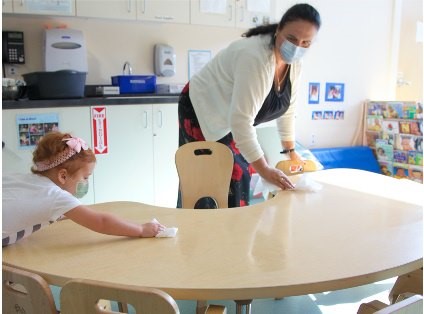 Teacher and child cleaning the table after lunch.