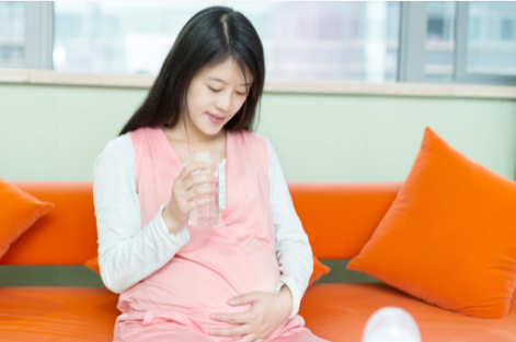 Pregnant woman sitting down with her hand on her belly.