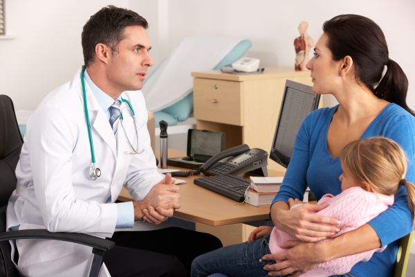 Médico hablando con una madre que está con su niña.