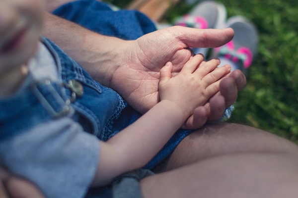 Mano de un niño pequeño sobre la mano de un adulto.