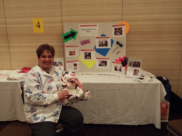 A dental hygenist liaison showing a class a large stuffed animal that has a huge mouth full of smiling teeth.