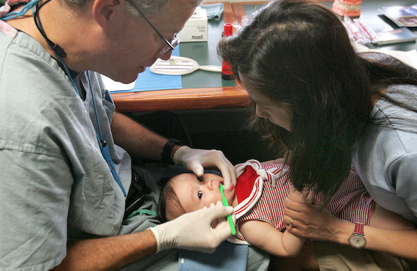 Dentista y asistente examinando los dientes de un niño.