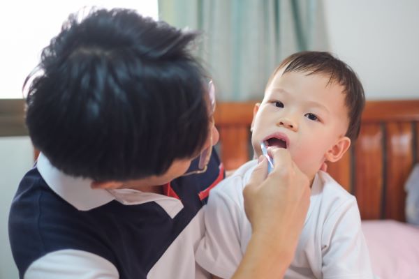 Padre cepillando los dientes de un niño pequeño.