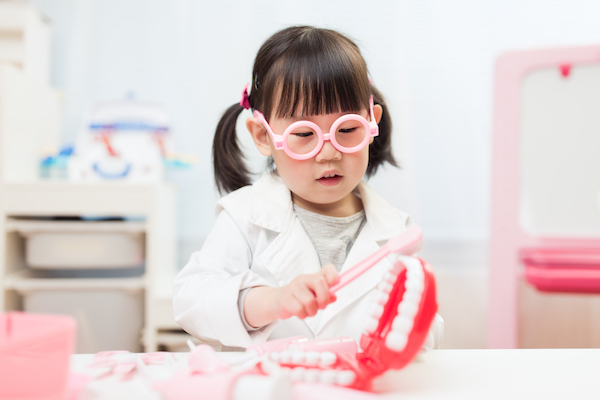 Niña jugando con unos dientes y unas encías gigantes de juguete.