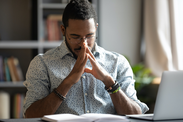 Man appearing to be under stress with his fingers tented together at his chin.