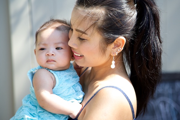 A mother holding her young daugher up to her cheek.