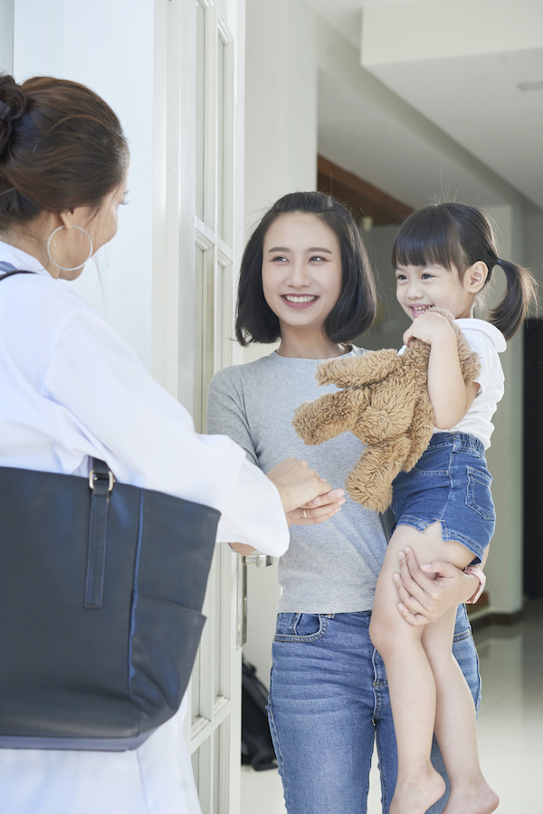 Parent and child greeting a home visitor at the front door.