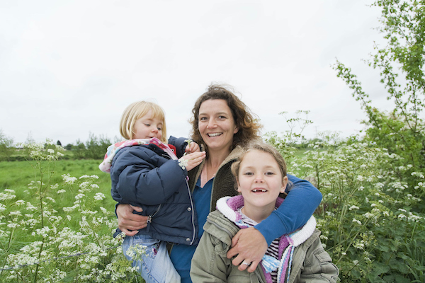 Mom and two children outdoors in a rural setting.