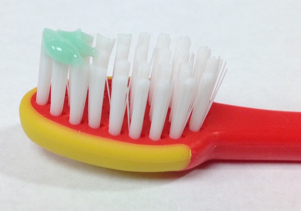 Toothbrush with a rice-sized smear of toothpaste.