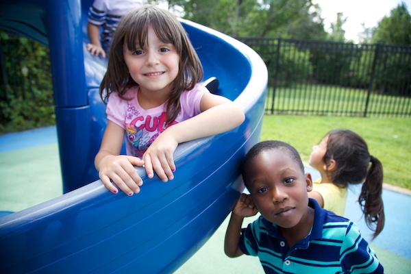 A girl and boy playing on a slide in the playground.