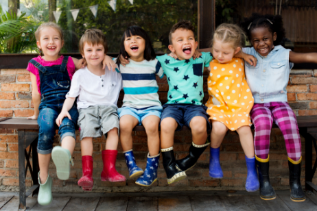 Six children sitting on a table with their arms around each other.