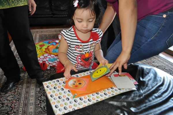 Young girl looking at various smiley faces.