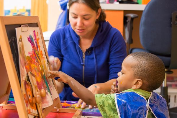 Woman and child looking at art on an easel.