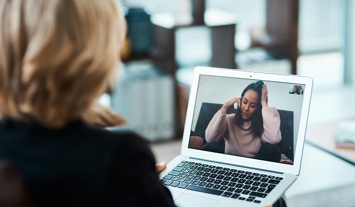 Woman talking with a colleague using a laptop.