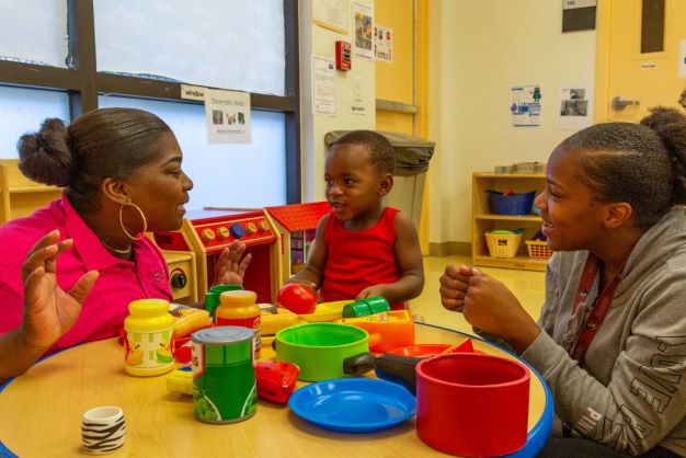 Children with teacher at a table talking.