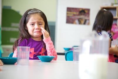 Niña secándose las lágrimas de las mejillas.