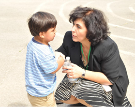 Un adulto en cuclillas hablando con un niño que parece estar triste.