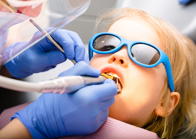 Niño pequeño sentado en el sillón del dentista recibiendo tratamiento dental.