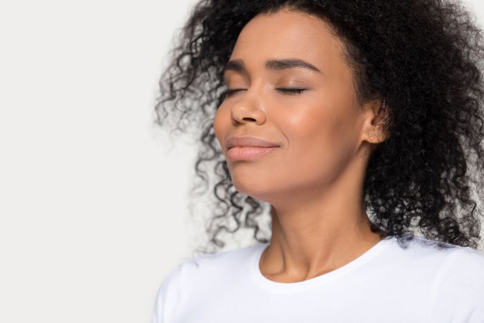 Mujer sentada y respirando profundo para relajarse.