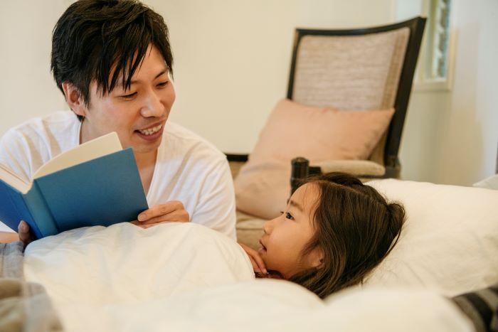 Father reading a bedtime story to his young daughter.