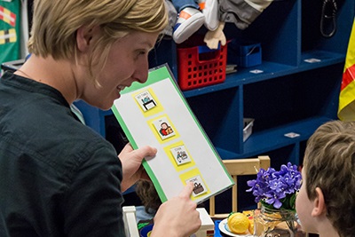 Teacher showing a graphic card to a child and sharing directions to follow.