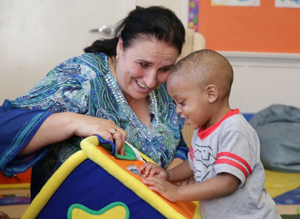 A woman and young boy reading a book together while in class.