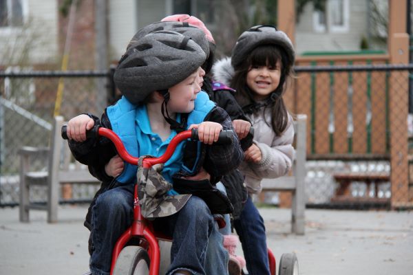 Niños con cascos montan en bicicleta al aire libre.