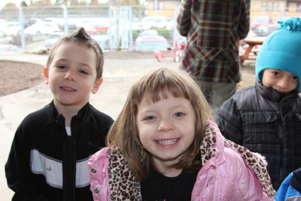 Niños sonrientes llevan puestos abrigos de invierno.