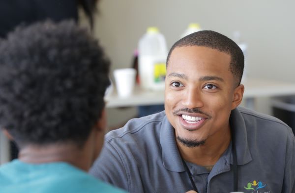 A smiling man talking to a woman.