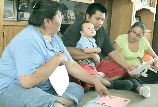 Adults with child looking over papers while sitting on floor.