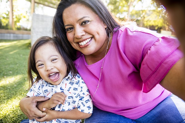 Smiling mother and daughter outdoors.