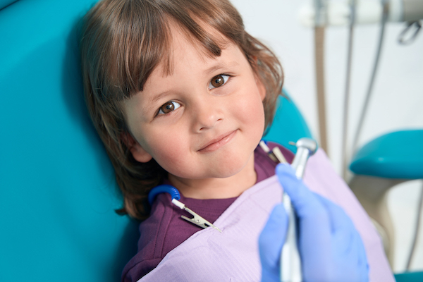 A young child sitting in the dentist's chair ready to have a dental checkup.