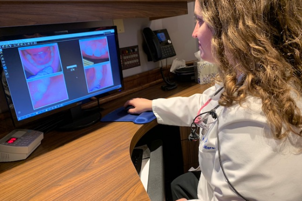 Dentist looking at x-rays on a computer monitor.