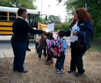 Niños bajo supervisión mientras suben y bajan del autobús escolar.