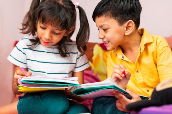 A young boy and girl writing in their notebooks.