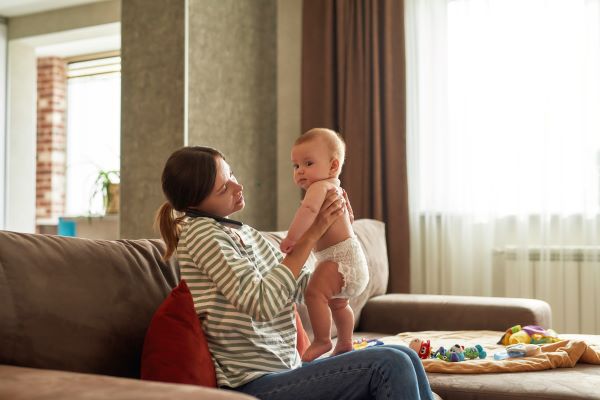 Una madre ayudando a su bebé a pararse en su regazo.