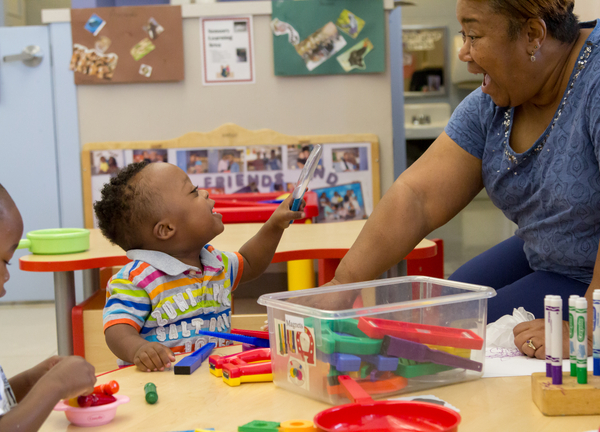 Child reaching up to give a high-five to teacher.