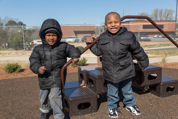 Two young boys bundled up wearing heavy coats playing outdoors on a cold day.