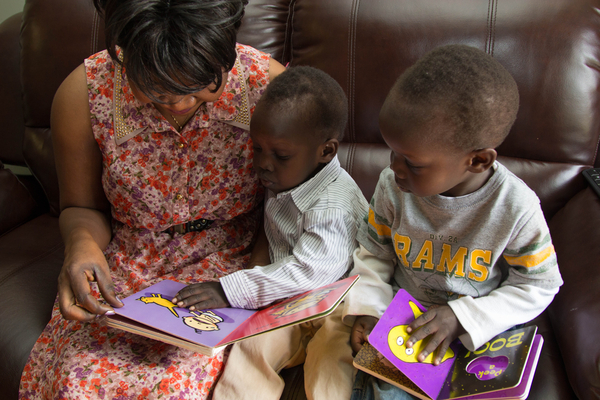 Teacher and two young boys reading together.