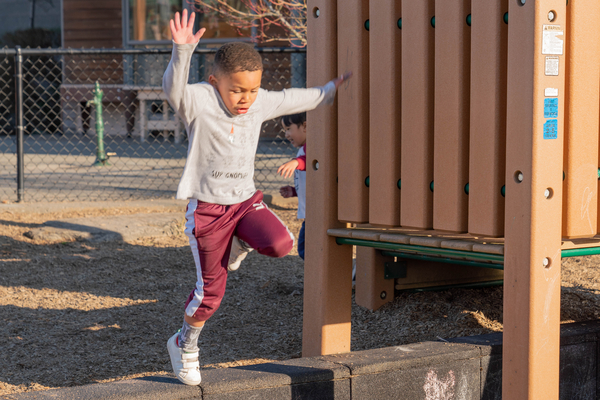 Young boy skipping around a the playground.