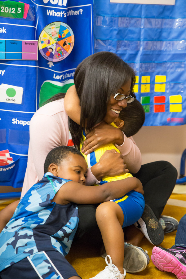 Teacher being hugged by two young boys.