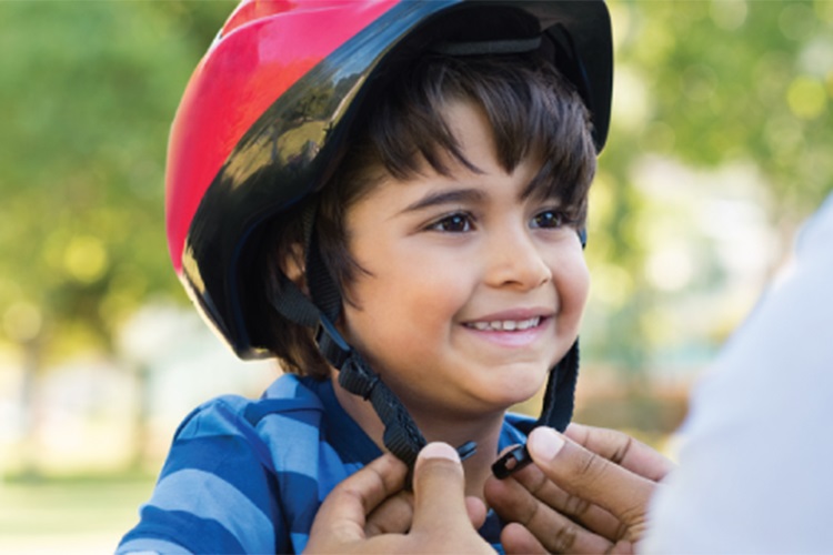 Adult helping a child to tie the bike helmet.